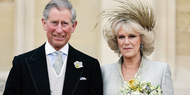 Prince Charles in a suit next to his bride Camilla wearing a bridal gown