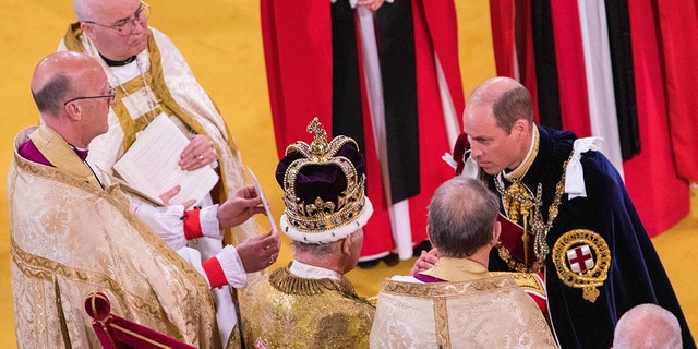 Prince William in royal regalia kneeling in front of his father King Charles