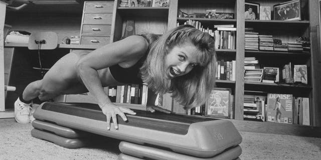 Denise Austin doing a push-up in workout gear from her home