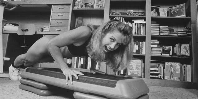 Denise Austin doing a push-up in workout gear from her home