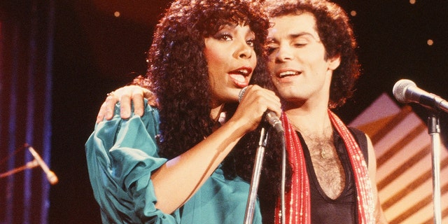 Donna Summer wearing a green dress singing next to Bruce Sudano