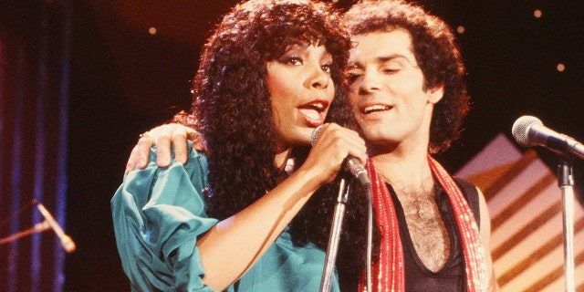 Donna Summer wearing a green dress singing next to Bruce Sudano