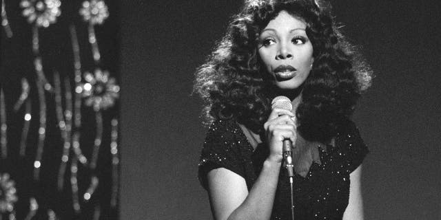 A black and white photo of Donna Summer holding a mic