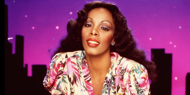 A close-up of Donna Summer leaning in wearing a floral dress