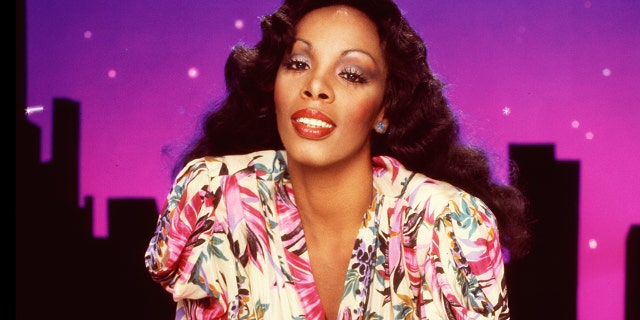 A close-up of Donna Summer leaning in wearing a floral dress