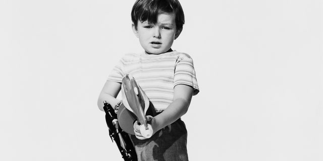 A young Jerry Mathers wearing a striped shirt and holding a toy