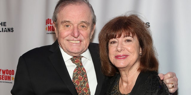 Jerry Mathers in a suit and tie smiling next to his wife