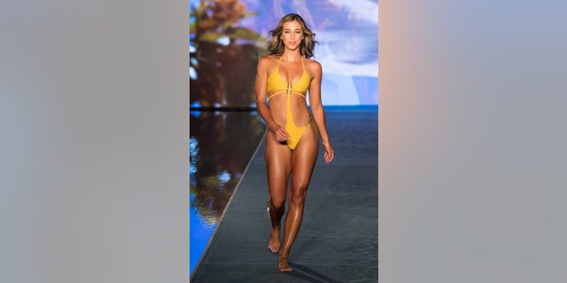 Kate Austin wearing a yellow one piece on the runway