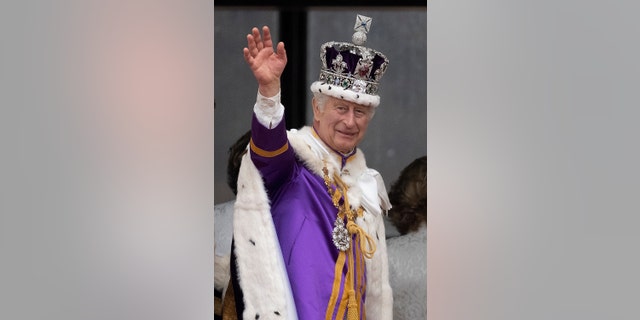 A close-up of King Charles in royal regalia waving to the croud