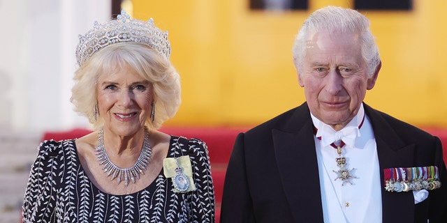 Queen Camilla in a black and white dress with a tiara next to King Charles in a suit