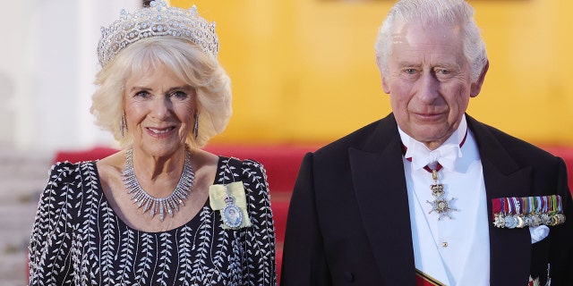 Queen Camilla in a black and white dress with a tiara next to King Charles in a suit