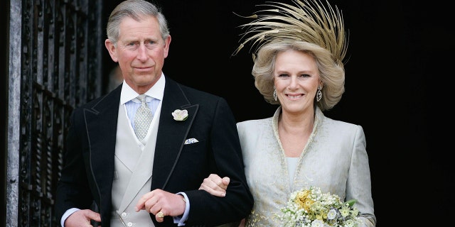 King Charles in a grooms suit and Camilla in a bridal gown with a golden fascinator on their wedding day