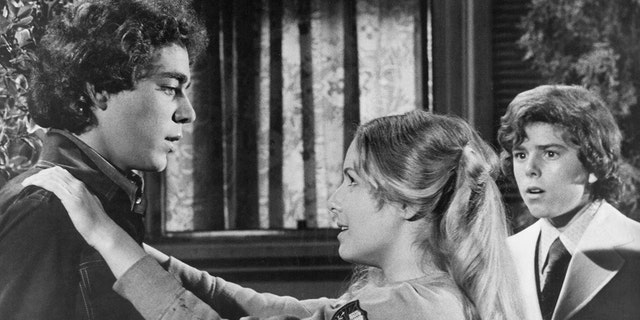 Kym Karath putting her arms around Barry Williams while filming The Brady Bunch