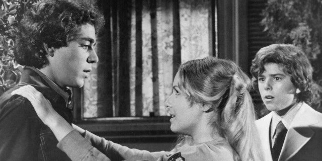 Kym Karath putting her arms around Barry Williams while filming The Brady Bunch