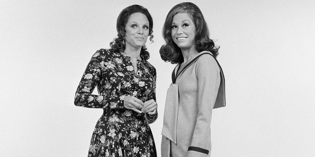 Valerie Harper leaning in to Mary Tyler Moore wearing a floral dress