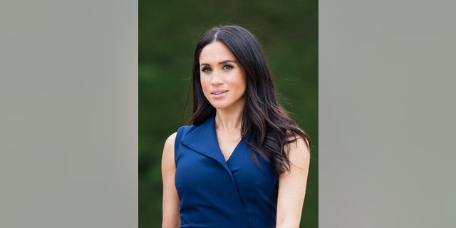 A close-up of Meghan Markle wearing a sleeveless blue dress