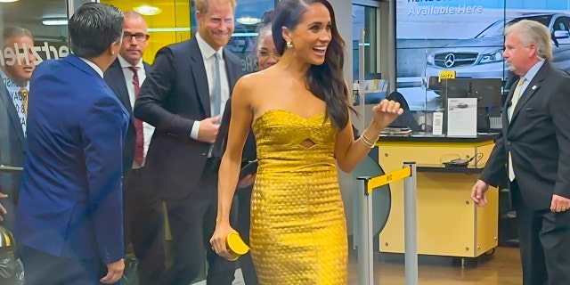 Meghan Markle wearing a gold dress arriving to the Women of Vision awards