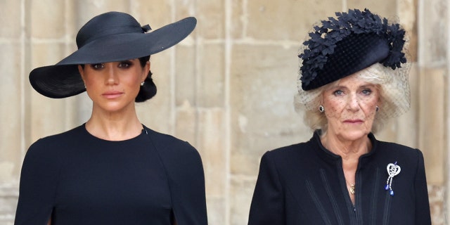 Meghan Markle and Queen Camilla, both wearing black, standing next to each other