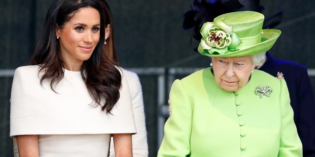 Meghan Markle in a beige dress sitting next to Queen Elizabeth in a lime green dress