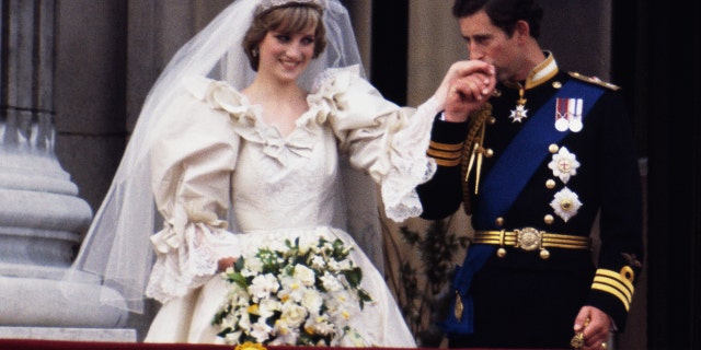 Princess Diana in a bridal gown having her hand kissed by her groom Prince Charles