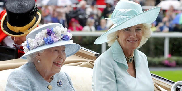 Queen Elizabeth in a blue dress next to Camilla in a lighter blue dress sitting in a royal carriage