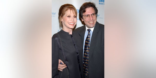 Marty Tyler Moore in a dark suit being embraced by Dr. Robert Levine wearing a matching suit, a blue shirt and a colorful tie