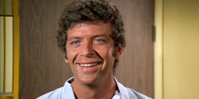 A close-up of Robert Reed wearing a white shirt and smiling as Mike Brady