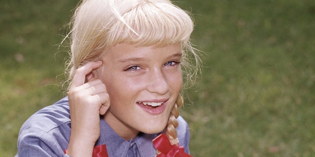 Susan Olsen as Cindy Brady in a blue bloouse and red pigtails