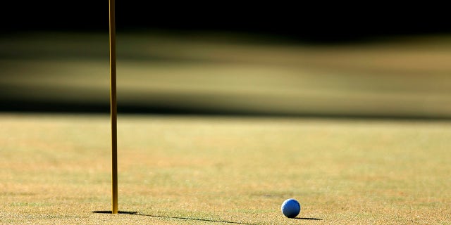 Pelota de golf al lado del hoyo