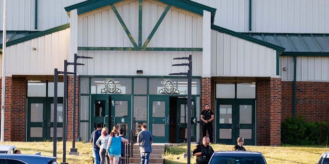 Law enforcement stand outside of Henryetta High School on Monday