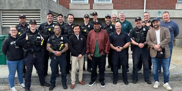 Kenan Thompson with Newport Governor Xay Khamsyvoravong center around police officers of the NPD