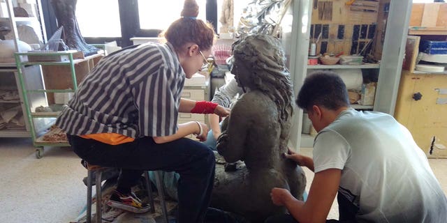 sculptors in studio working on mermaid statue
