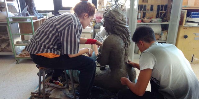 studio sculptors working on mermaid statue