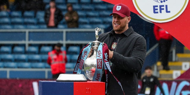 JJ Watt carries the league winner's trophy