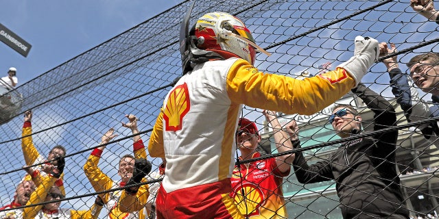 Josef Newgarden climbs the catch fence