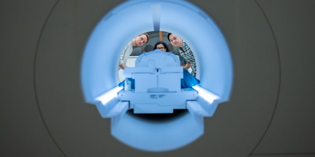 Alex Huth (esquerda), Shelly Jin (centro) e Jerry Tang (direita) se preparam para coletar atividade cerebral