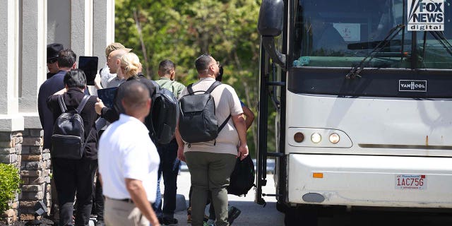 people getting off of a bus with bags