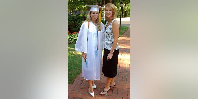 Natalee is in a white cap and gown as she stands with her mother, Beth