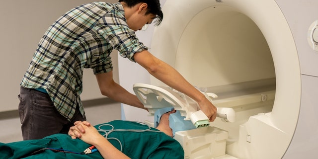 Jerry Tang puts a patient in an fMRI scanner