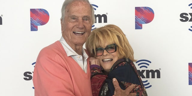 Pat Boone in a pink sweater hugging a smiling Ann-Margret in glasses