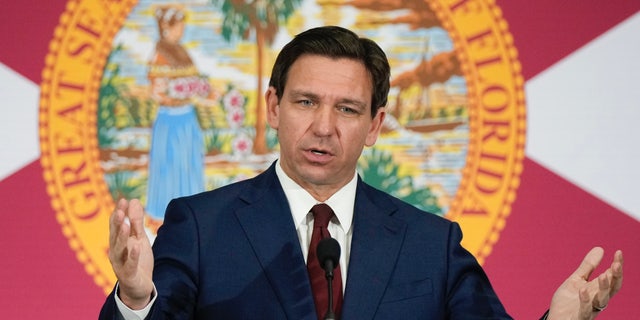 Ron DeSantis speaking in front of a Florida flag