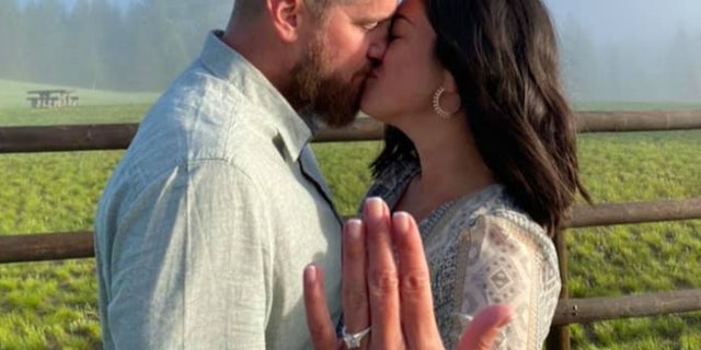 Aric Hutchinson kisses Samantha Miller as she shows off her engagement ring.