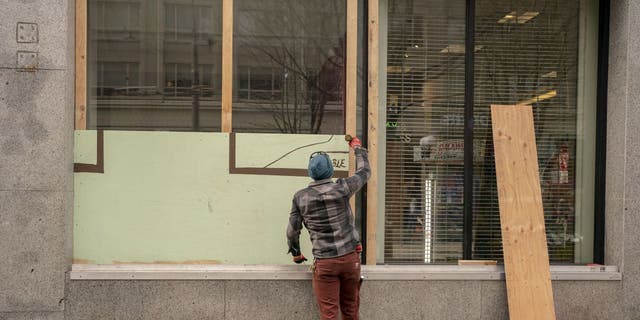 man boards up Seattle storefront