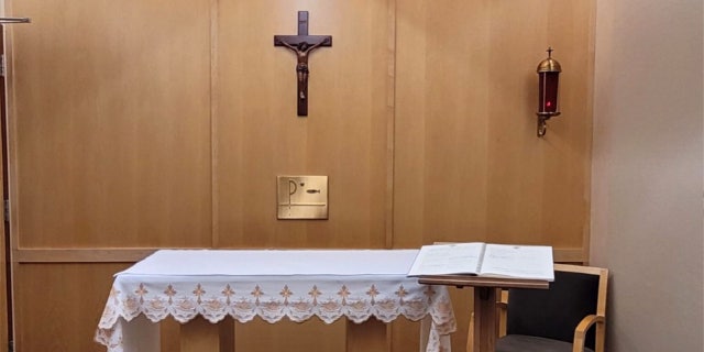 chapel with crucifix center, sanctuary candle at right