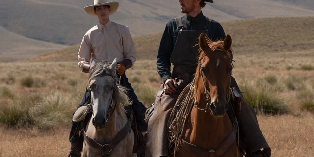 Kodi Smit-McPhee and Benedict Cumberbatch ride horses in a scene from The Power of the Dog