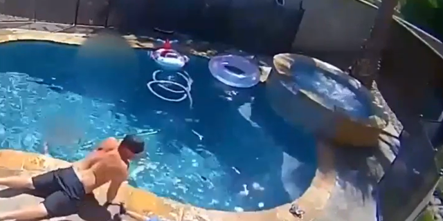 Firefighter laying down outside pool with son