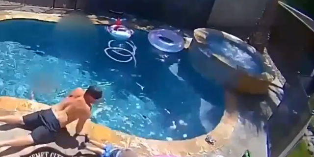 Firefighter laying down outside pool with son