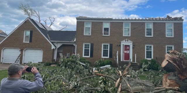 A man photographs a home damaged by a tornado in Virginia Beach