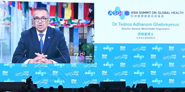 A screen shows World Health Organization (WHO) chief Tedros Adhanom