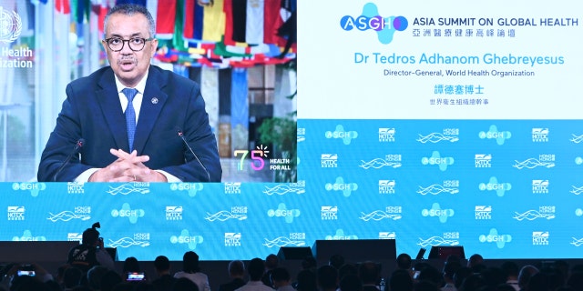 A screen shows World Health Organization (WHO) chief Tedros Adhanom